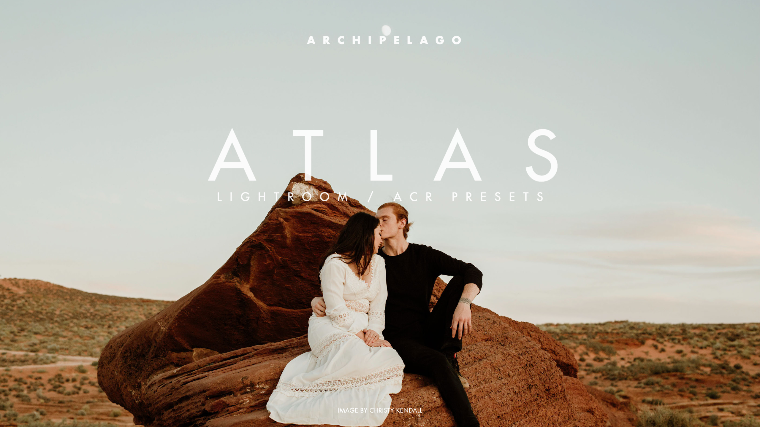 A couple kisses in the desert while displaying Atlas Lightroom presets by Archipelago.