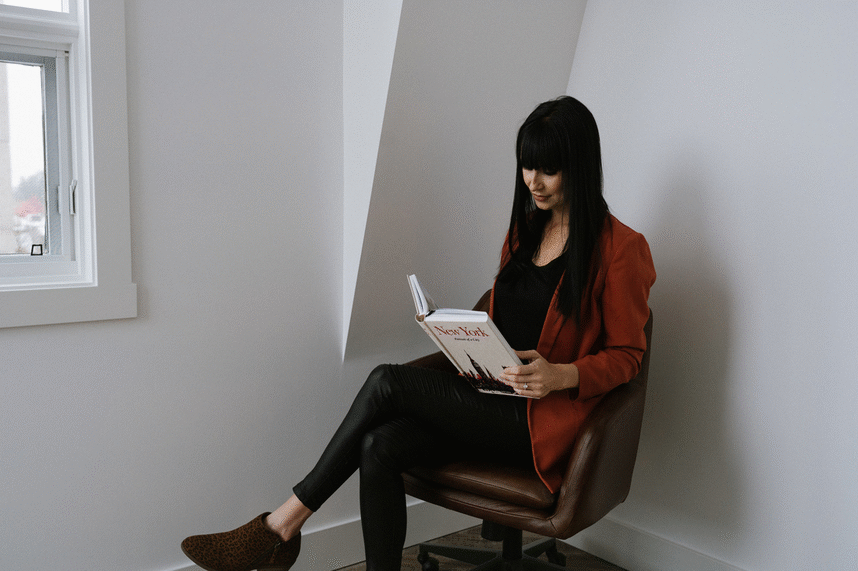 GIF of a black haired beauty reading a book in a chair and then closing it and getting up to go work on her marketing services with meet pepper.