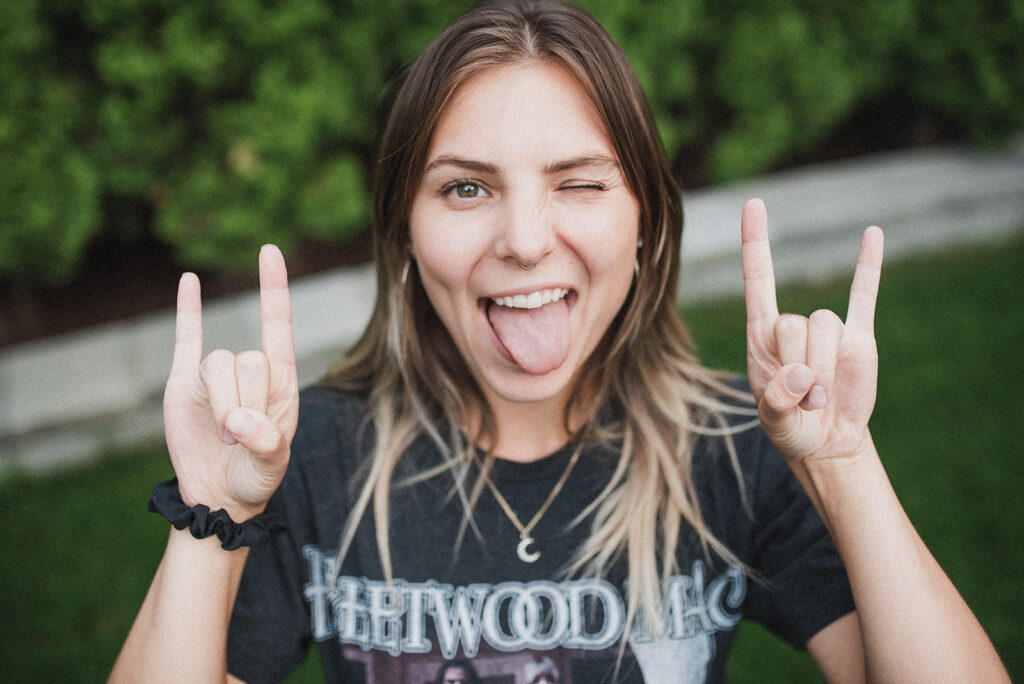 Meet Pepper's content creator Kayleigh, who offers email marketing and newsletter training for photographers, sticking her tongue out while winking and showing devil horn hands.