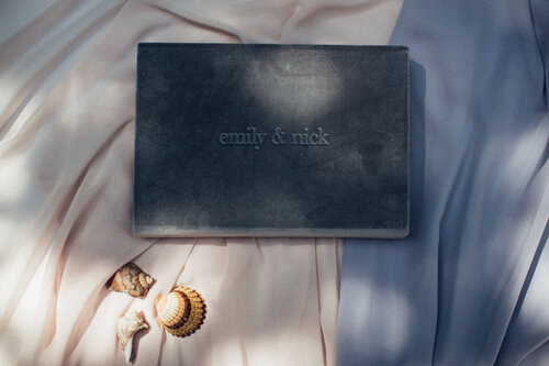 Grey print box with a custom stamp on top of a blue and baby pink background.