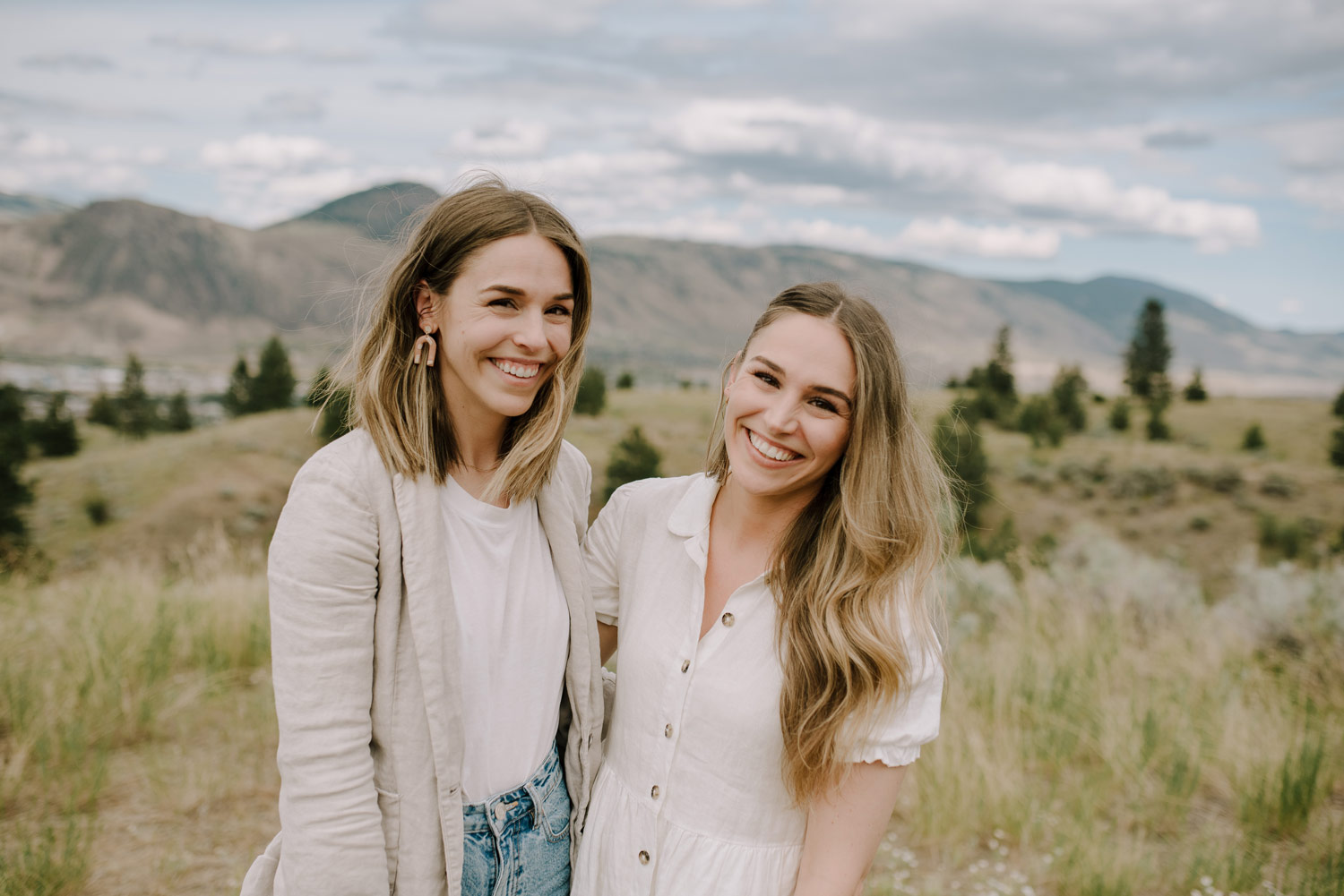 bria gatien and her friend hug each other and smile with kamloops bc rolling hills in the background during a branding photography session with meet pepper