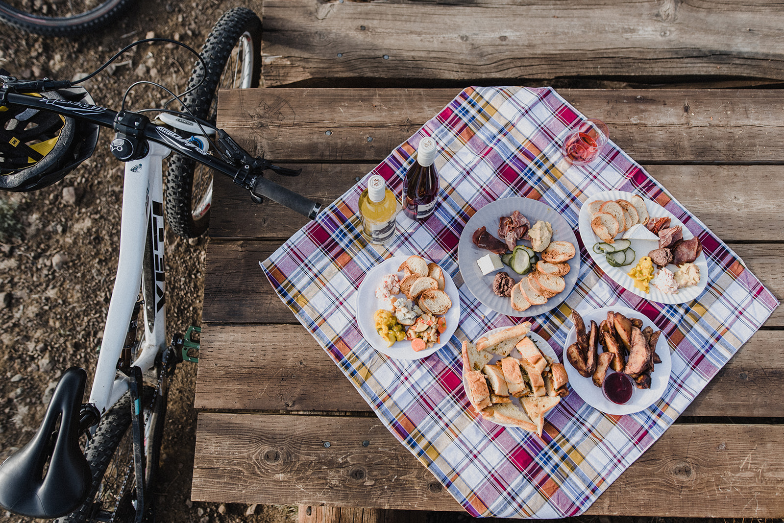 a picnic sits on a picnic table with a couple bottles of wine and a mountain bike during a branding photography shoot with meet pepper in kamloops
