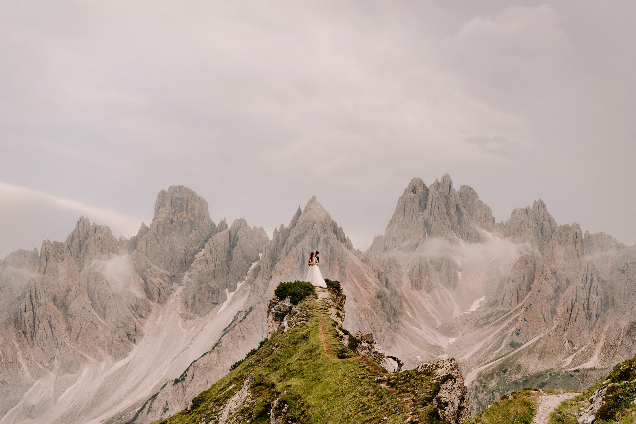 bride and groom hug it up on the tip of a green path with jagged brown peaks behind them as a metaphor for how good it feels to be found on google