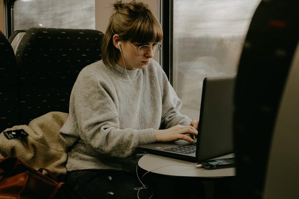 a photographer editing images on her laptop while on in transit to try to meet a photography turnaround time.