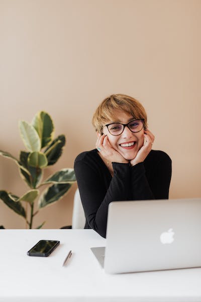 woman in glasses leans over her desk interested to learn how to avoid burnout as a creative entrepreneur