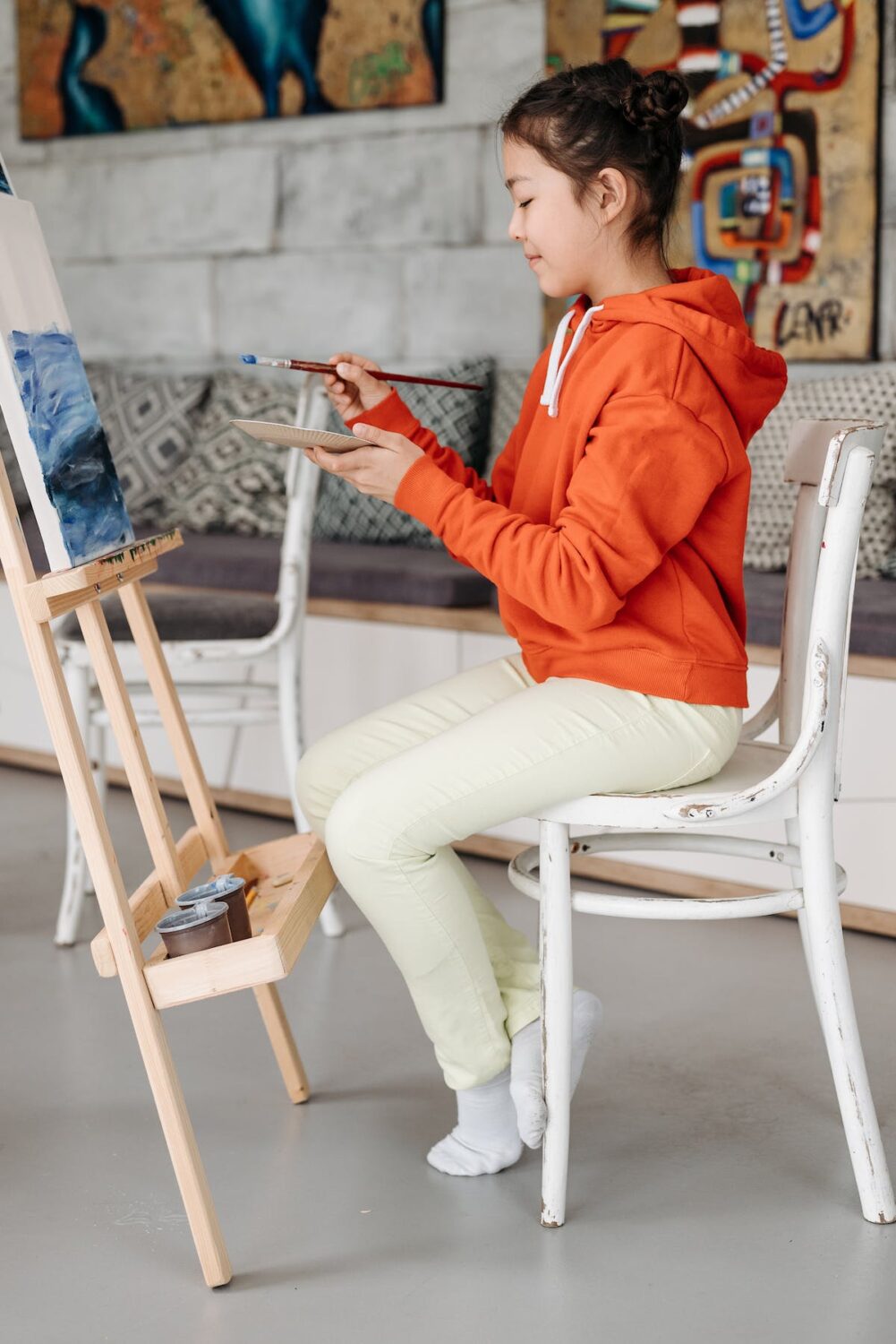 young woman sits in front of an easel painting to keep her creative passion alive and avoid burnout
