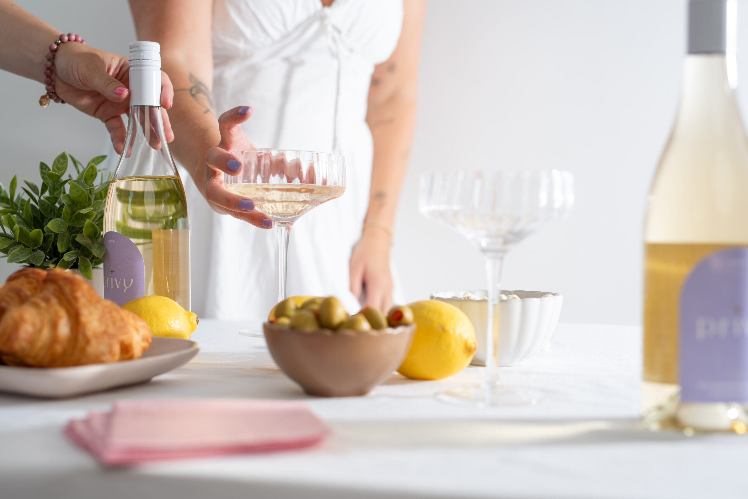 Lifestyle content shoot featuring Privy wine with styled table setting, fresh lemons, and glassware, captured for social media marketing and brand photography