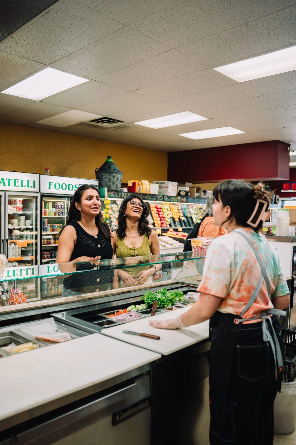 Two women smile while ordering at the deli counter inside Fratelli Foods in downtown Kamloops.