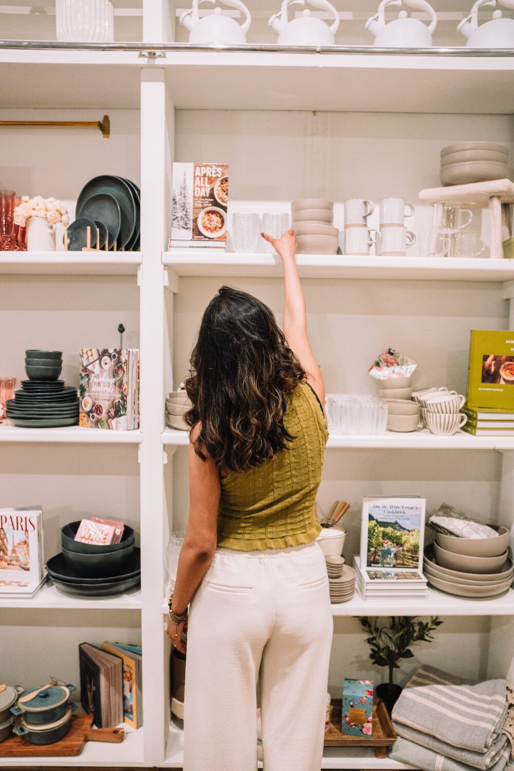 A shopper reaches for dishes on a styled home goods shelf inside Jardines Domaine Home in downtown Kamloops.