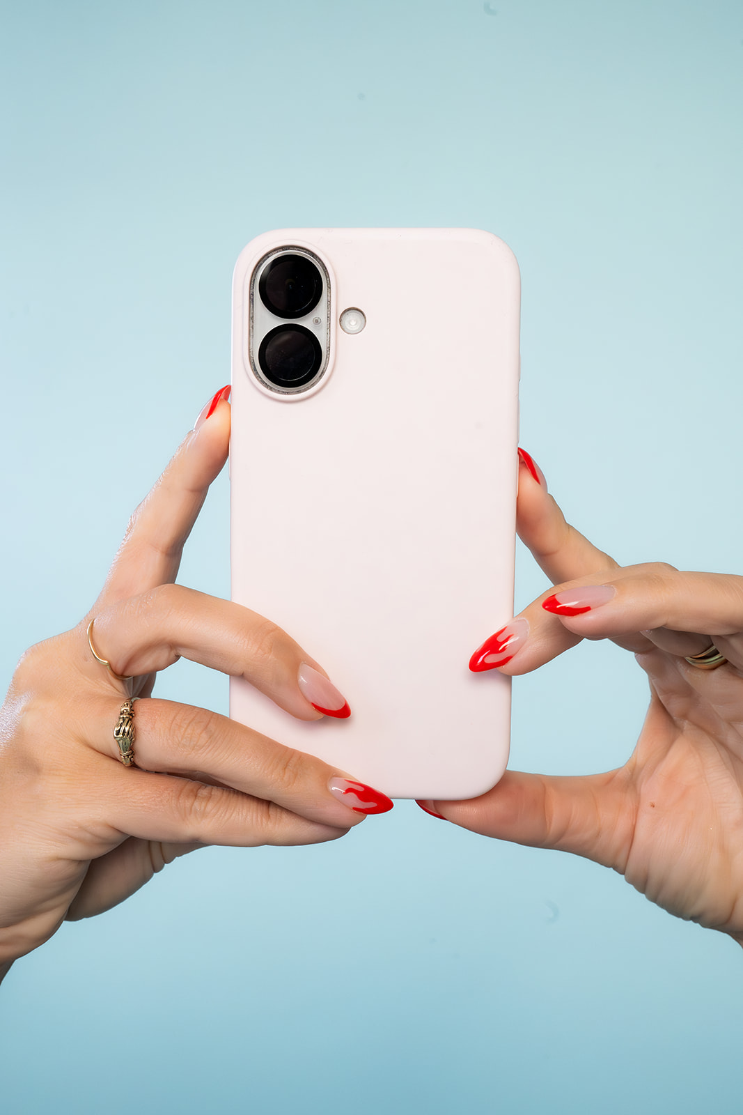 Hands holding a smartphone against a blue background, representing mobile content creation and social media marketing strategy