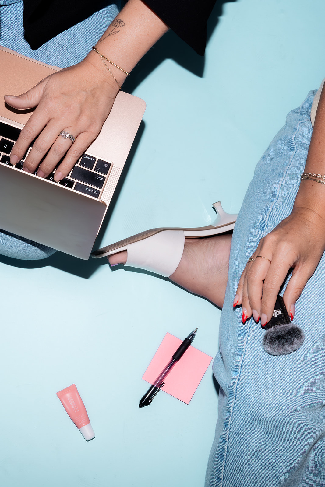 Flat lay of laptop, makeup, and accessories on blue background, representing content planning and branding for social media marketing