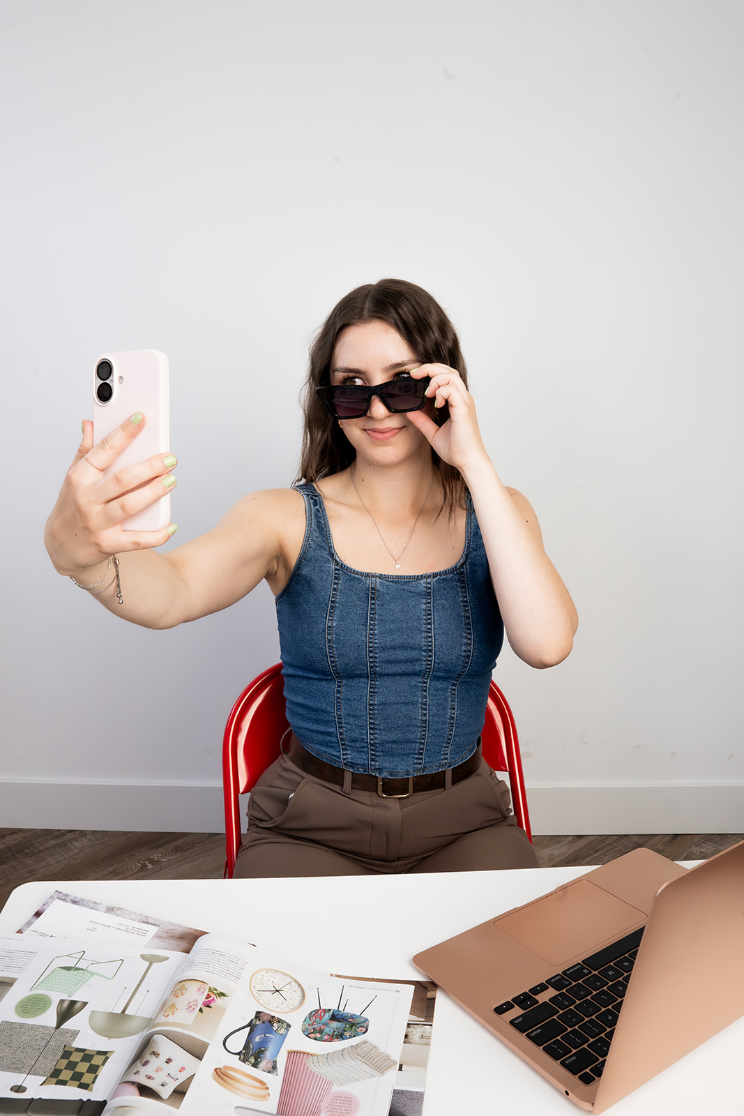 Woman taking a selfie at a desk with mood boards and marketing planning materials