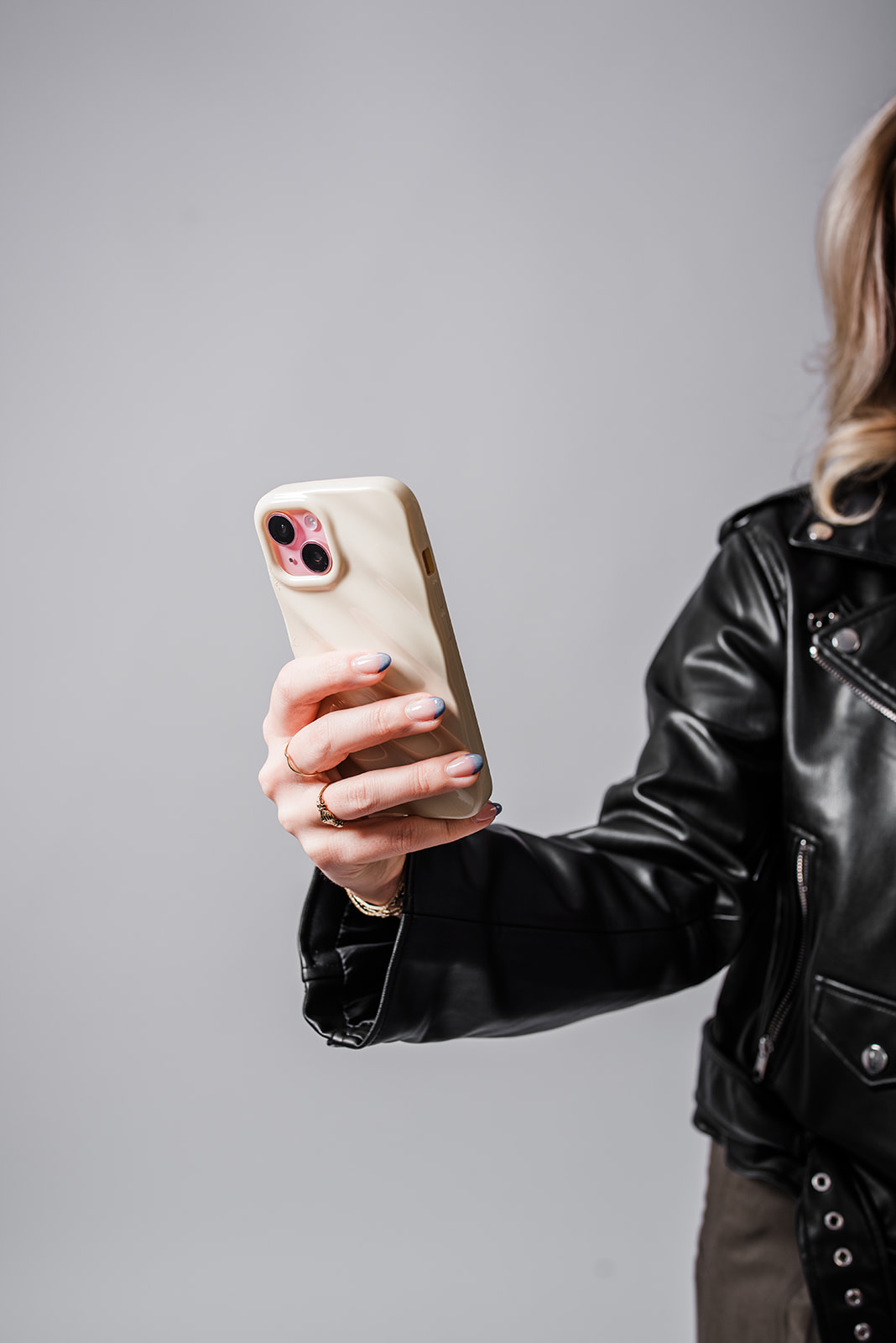 Woman holding a phone for selfie-style social media content creation in a studio setting