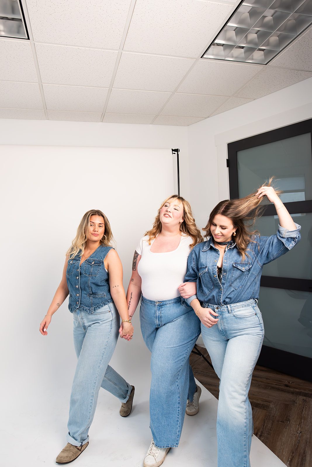 Three women from the Pepper Marketing team posing together in a bright studio setting