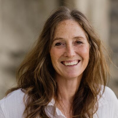 Professional headshot of a woman smiling outdoors in natural light, suitable for professional branding or business profiles.