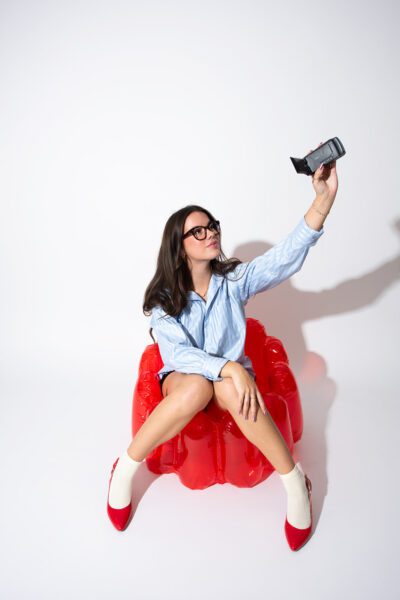 Woman sitting on a red inflatable chair holding a camera for creative content production