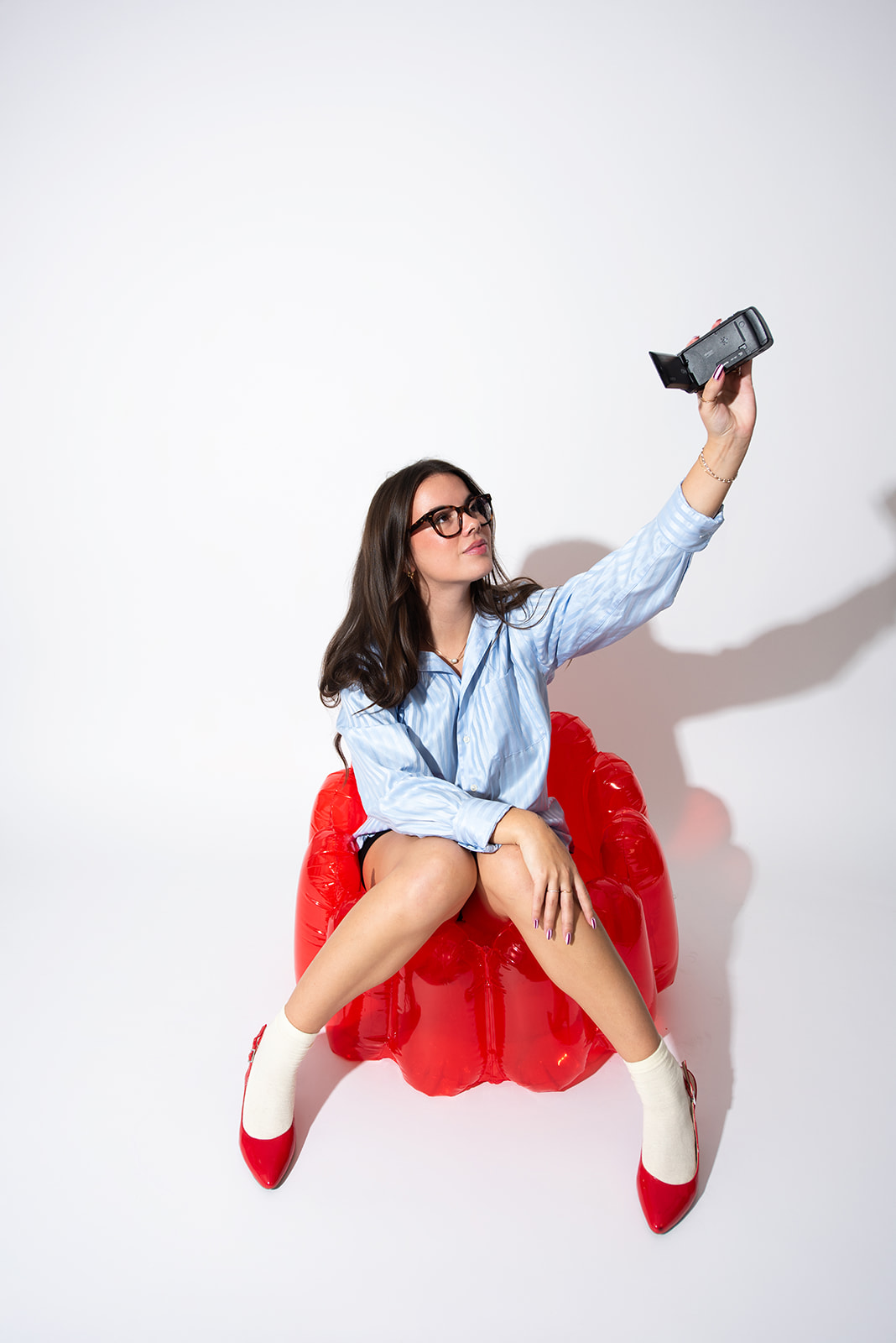 Woman sitting on a red inflatable chair holding a camera for creative content production