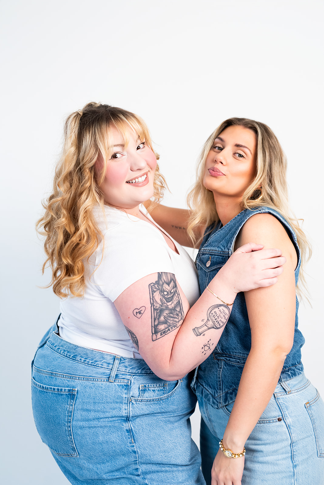 Two women posing together in denim outfits and smiling at the camera during a fashion and lifestyle branding photoshoot.