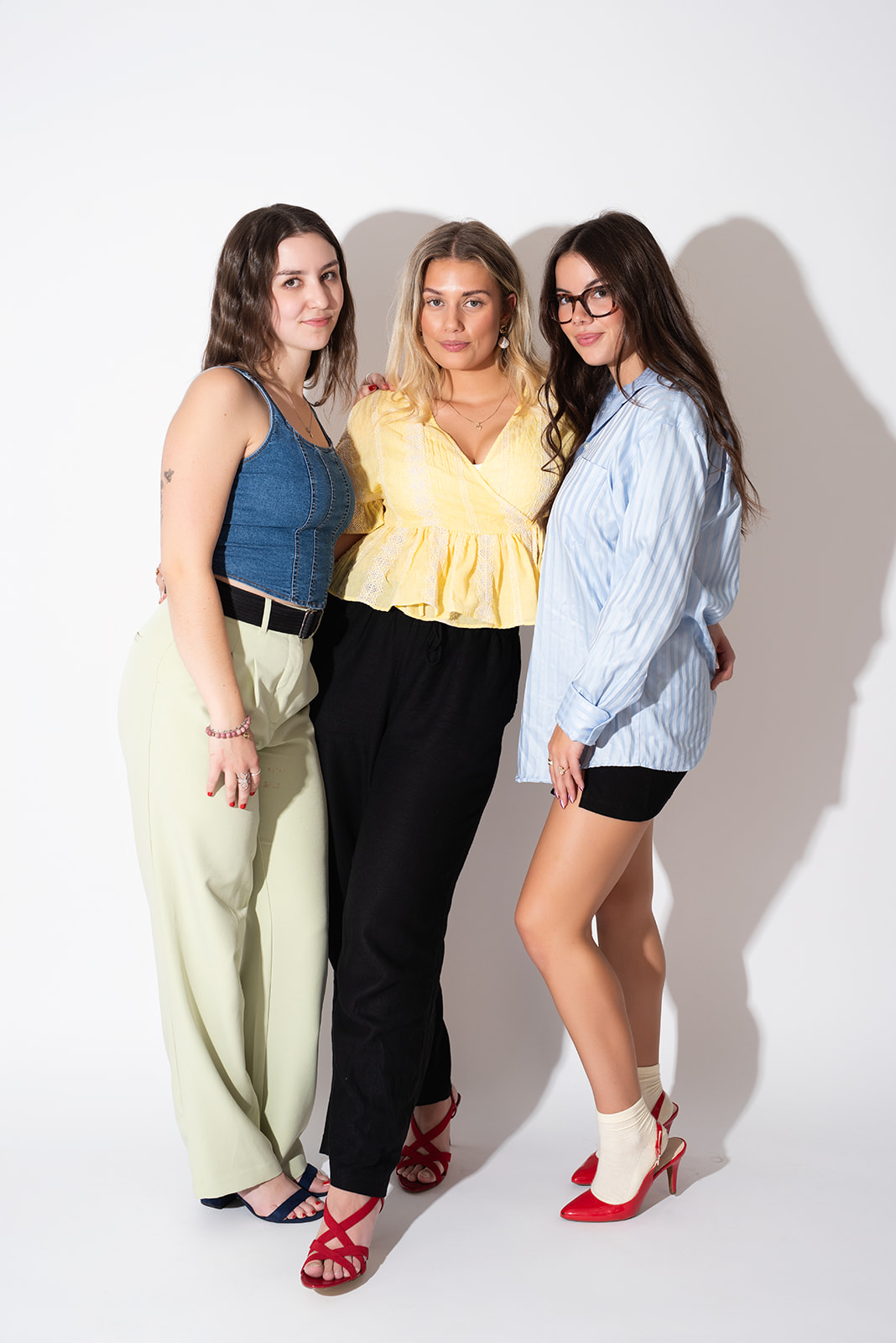 Three women standing together in a studio setting, styled in modern, fashion-forward outfits, representing the creative team behind Pepper, a branding and marketing agency in Kamloops focused on strategy, content, and design.