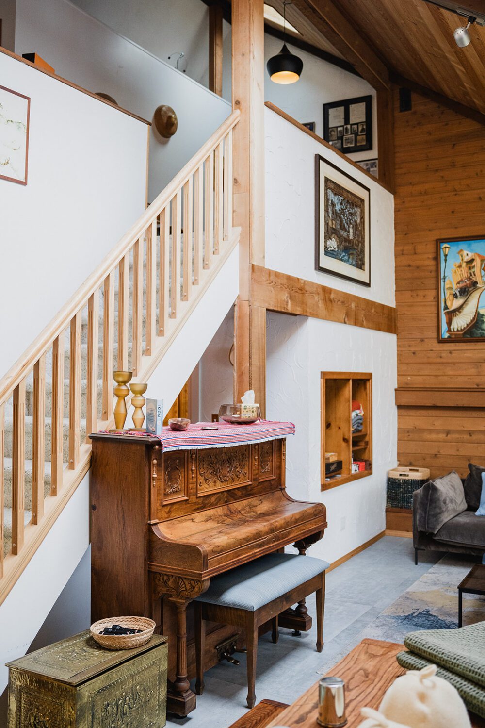 Interior view of The Spot featuring a wooden staircase, vintage piano, art-covered walls, and cozy retreat-style decor.