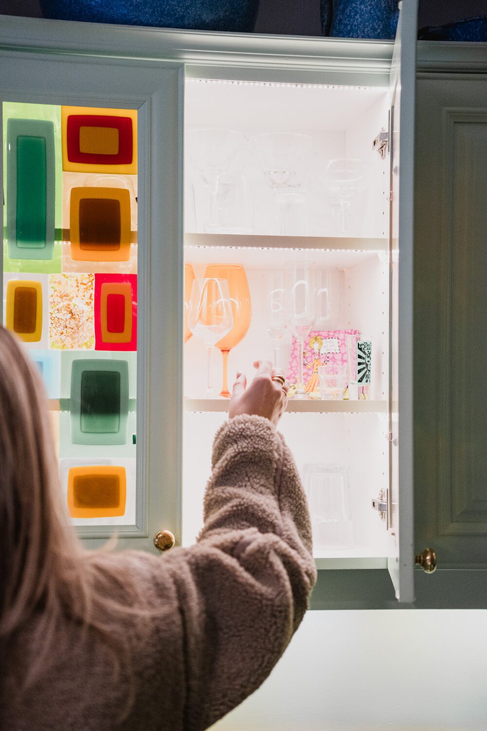 Guest reaching for glassware inside a colourful cabinet during a brand retreat at The Spot.