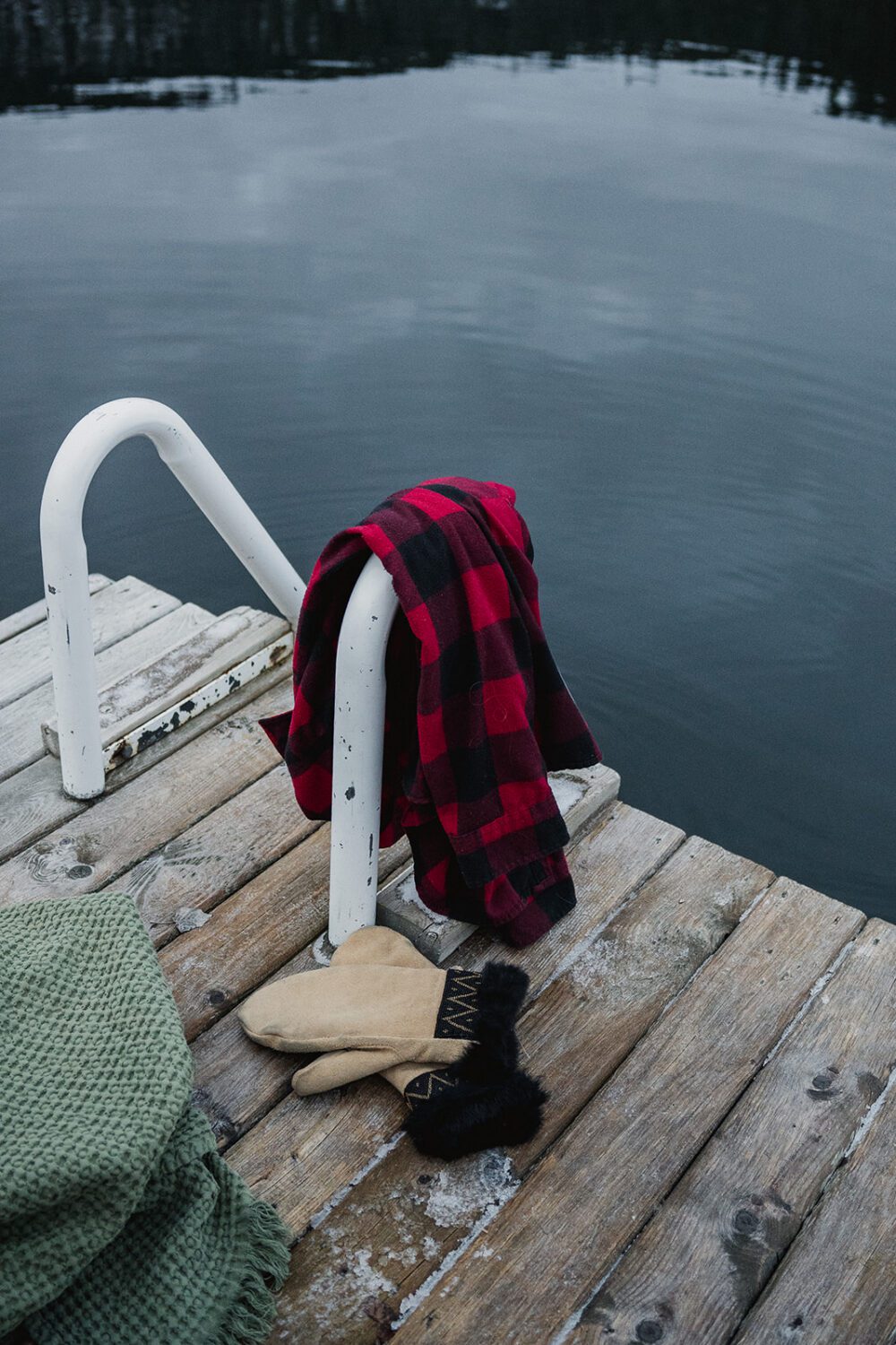 Towels, mittens, and lake gear resting on the snowy dock beside Paul Lake at The Spot.