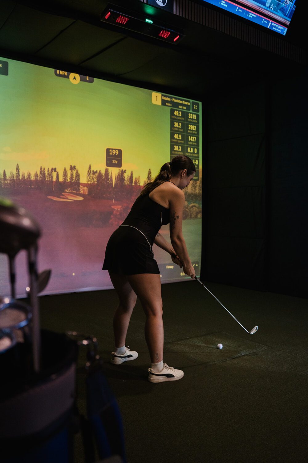 Close-up of a golfer taking a swing inside a Kamloops Virtual Golf simulator.