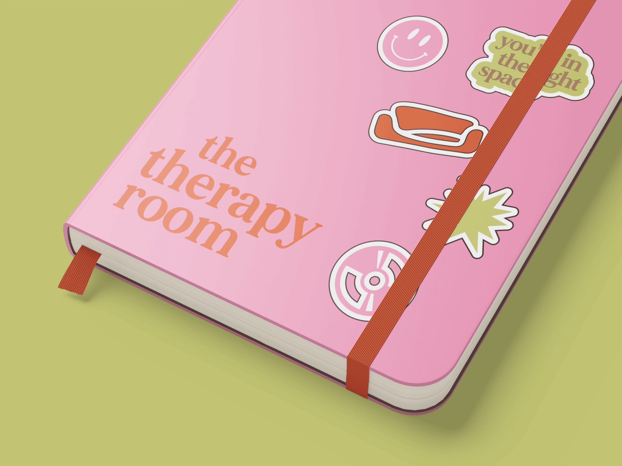 Pink The Therapy Room notebook featuring the logo, couch icon, and branded sticker graphics created by Pepper through a Visual Identity package.